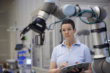 Fokussierter reifer Techniker bei der Untersuchung eines Roboterarms - RBF09058