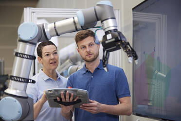 Kollegen diskutieren über Roboterarm in moderner Fabrik - RBF09061