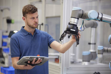 Engineer testing modern robotic arm in factory - RBF09063