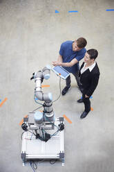 Technician explaining machine to businesswoman in industry - RBF09076