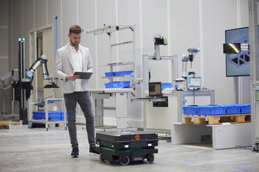 Ingenieur, der einen modernen mobilen Roboter in der Industrie bedient - RBF09107