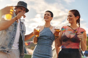 Friends have fun in the festival camp, sharing laughter and ice-cold beers, immersing themselves in the joyous atmosphere and embracing the carefree spirit of the event. This photo has intentional use of 35mm film grain. - JLPPF02184