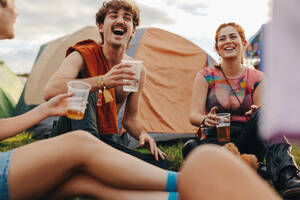 Young people congregate at the festival camp, relishing refreshing beers, and delighting in shared laughter, fostering a sense of togetherness and creating memories that will last. This photo has intentional use of 35mm film grain. - JLPPF02198