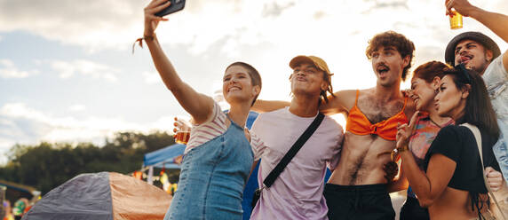 Eine Gruppe von Freunden fängt einen lebhaften und unvergesslichen Moment auf einem Sommermusikfestival ein und verewigt ihre Verbundenheit und Begeisterung mit einem fröhlichen Selfie. Die absichtliche Verwendung von 35-mm-Filmkorn verleiht einen nostalgischen Touch - JLPPF02206