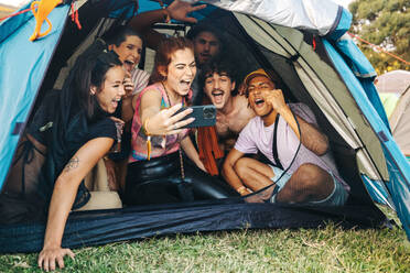 Eine Gruppe von Freunden fängt fröhliche Momente auf einem Sommerfest ein, macht Selfies und schafft Erinnerungen während eines Campingurlaubs - JLPPF02226