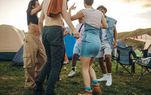 Diverse group of young people having fun together, celebrating at a summer festival camp. Men and women dancing to the music in an authentic festival atmosphere. This photo has intentional use of 35mm film grain. - JLPPF02228