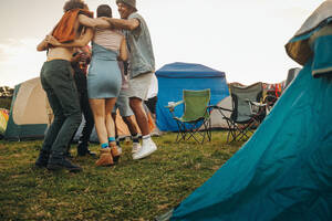 Group of young people gathered together in a circle, dancing and celebrating at a music festival. Friends having fun at a camp - the perfect picture of real summer festival vibes. This photo has intentional use of 35mm film grain. - JLPPF02230