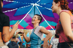 Friends unleash their inner dancers, moving and partying with infectious enthusiasm, as they have a fantastic time at the summer music festival. Happy young people having fun at a festival party. This photo has intentional use of 35mm film grain. - JLPPF02231