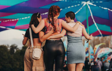 Female friends connect through their shared love for music and celebration, savoring every moment of the summer festival's exhilarating atmosphere. This photo has intentional use of 35mm film grain. - JLPPF02235