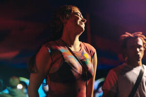 Woman embraces the night at a music concert, dancing and enjoying herself in the vibrant atmosphere. Young woman creating unforgettable moments of celebration at a festival. This photo has intentional use of 35mm film grain. - JLPPF02259