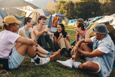 Group of friends gathers around, enjoying drinks together and creating cherished memories of an unforgettable festival experience, filled with laughter and joy. This photo has intentional use of 35mm film grain. - JLPPF02260
