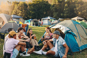 Friends at the festival camp bond over laughter, engaging conversations, and the shared enjoyment of their drinks, creating an atmosphere of warmth, camaraderie, and festival spirit. This photo has intentional use of 35mm film grain. - JLPPF02263