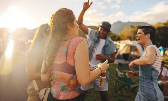 Friends come together and immerse themselves in the contagious festive spirit, dancing and celebrating in unison at a vibrant summer festival party. This photo has intentional use of 35mm film grain. - JLPPF02273