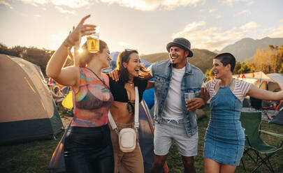 Friends having fun together, moving and celebrating with infectious energy at a vibrant summer music festival. Happy young people enjoying a summer festival camp. This photo has intentional use of 35mm film grain. - JLPPF02275