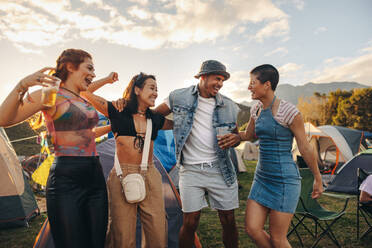 Young people embrace the spirit of summer, expressing their joy through vibrant dance moves, creating an atmosphere of celebration at a music festival. This photo has intentional use of 35mm film grain. - JLPPF02276