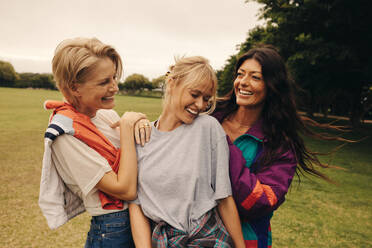 Caucasian female friends in their 30s enjoying a fun day of socializing at the park, bonding over laughter and playful activities. They are happy and authentically enjoying each others company. This photo has intentional use of 35mm film grain. - JLPPF02306