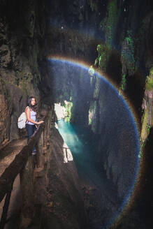 Calm female traveler standing on edge near fence and admiring picturesque scenery of river and mountains in cave during trip to Zaragoza city - ADSF44445