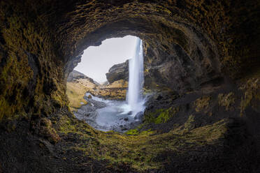 Picturesque view of rapid Seljalandsfoss waterfall flowing through rocky mountains covered with grass in Iceland - ADSF44604