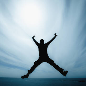 Man jumping against cloudy sky - ADSF44619