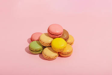 Appetizing various sweet colorful macaroons placed in heap on pink background of studio - ADSF44641