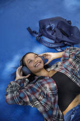 Happy student lying and listening to music - IKF00986