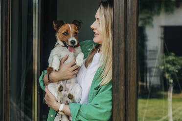 Woman holding dog near door - VSNF01122