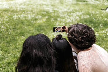 Eine Gruppe von Freunden hält einen lustigen Moment im Park mit einem mit dem Smartphone aufgenommenen Selfie fest - PBTF00034