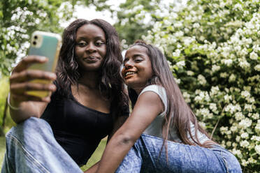 Eine Gruppe fröhlicher Frauen, die einen Moment des Glücks einfangen, indem sie ein Selfie in einem schönen Park machen - PBTF00035