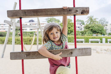 Playful girl climbing ladder at beach - IHF01466