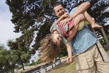 Smiling father carrying daughter at beach - IHF01468