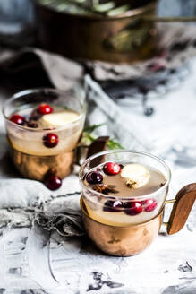 Becher mit Moscow Mule-Getränk mit Gewürzen und Preiselbeeren auf dem Tisch - SBDF04646