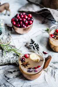 Becher mit Moscow-Mule-Getränk mit Preiselbeeren und Gewürzen stehen auf dem Tisch - SBDF04648