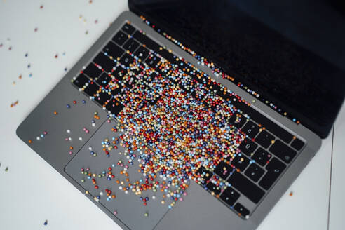 Multi colored pearls on laptop at desk - JOSEF19903