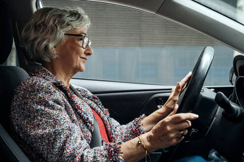 Smiling senior businesswoman driving car - GDBF00072