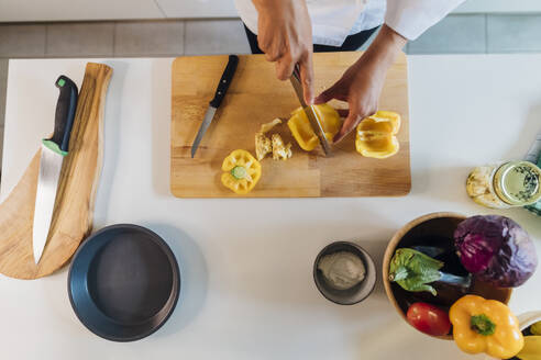 Koch schneidet gelbe Paprika in der Küche zu Hause - MEUF09147