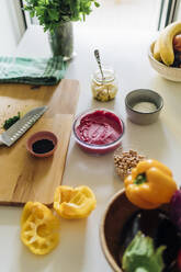 Schale mit Rote-Bete-Hummus mit Zutaten auf dem Tisch in der Küche zu Hause - MEUF09148