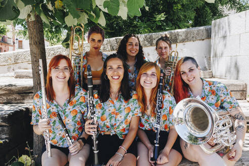 Happy women's folk group sitting together holding musical instruments - MRRF02649