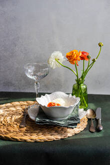 Table setting with Ranunculus flowers on concrete background - ADSF44686