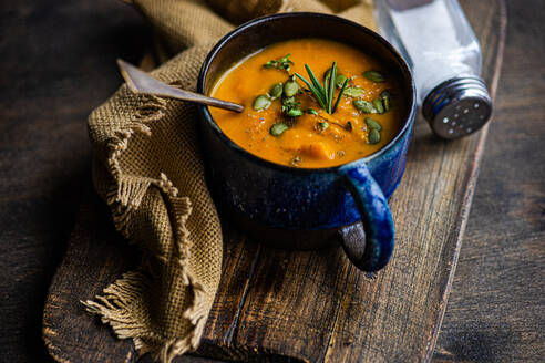 Tasty pumpkin cream soup with organic herbs and seeds in blue vintage ceramic bowl - ADSF44689