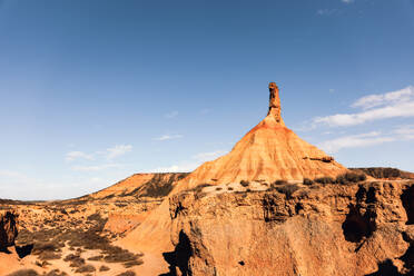 Picturesque view of rough stony formation with uneven surface and dry ground under blue sky in Bardenas Reales desert - ADSF44798