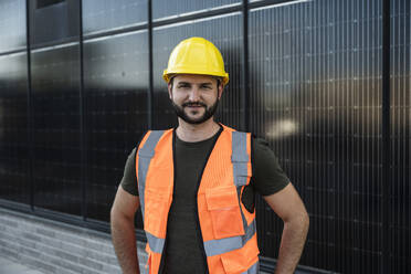 Smiling engineer standing in front of solar panels - UUF29335