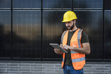 Ingenieur mit Tablet-PC vor einem Solarpanel - UUF29341