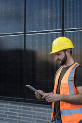 Ingenieur mit Tablet-PC vor Sonnenkollektoren - UUF29343