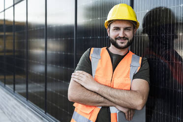 Lächelnder Ingenieur, der sich auf Sonnenkollektoren stützt - UUF29352