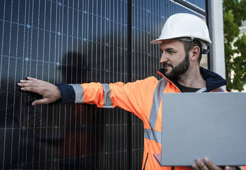 Ingenieur hält Laptop und berührt Solarzellen - UUF29369