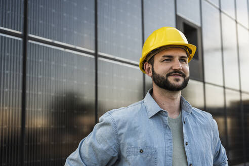 Smiling engineer with beard in front of solar panels - UUF29382