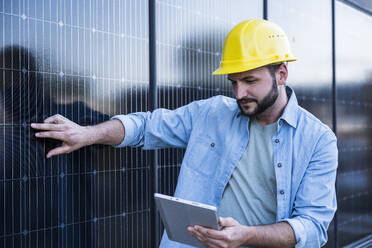 Engineer examining solar panels using tablet PC - UUF29390