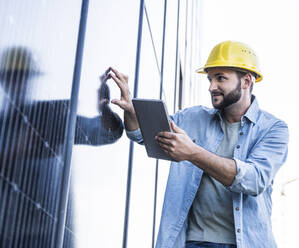 Engineer touching solar panels holding tablet PC - UUF29396