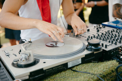 Cropped anonymous DJ playing music on mixing console during music festival - ADSF44913