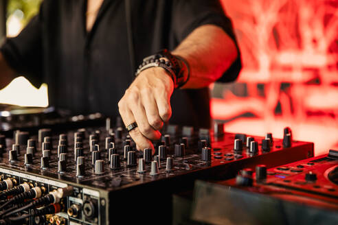 Cropped anonymous DJ playing music on mixing console during music festival - ADSF44914